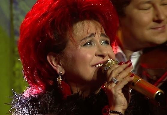 Bernadeta Kowalska zaangażowana w działalność charytatywną, w otoczeniu ludzi, z uśmiechem na twarzy.