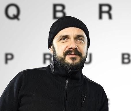 Uśmiechnięty portret Arkadiusza Jakubika, prezentujący jego przystępną osobowość.
