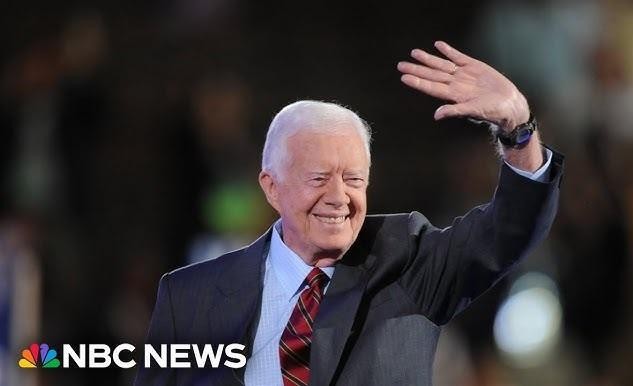 Jimmy Carter budujący dom dla Habitat for Humanity, w roboczym ubraniu, na placu budowy.