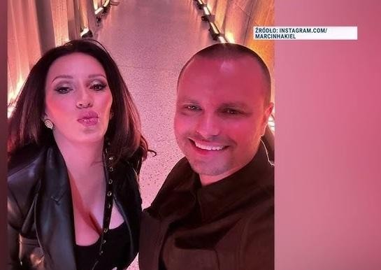 Portret Marcina Hakiela z uśmiechem, w tle subtelne rozmycie, sugerujące przestrzeń taneczną lub nowoczesne wnętrze.