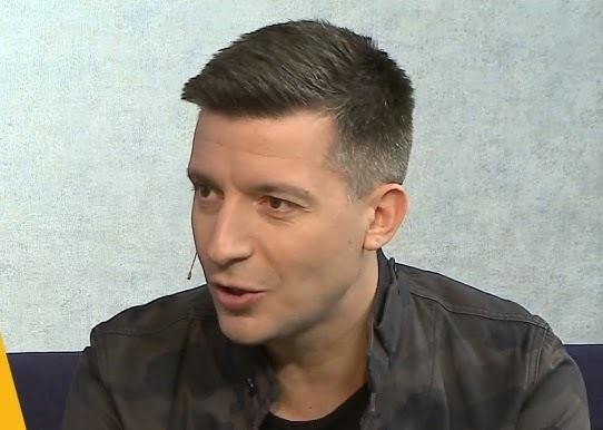 Michał Cessanis w scenerii podróżniczej, uśmiechnięty i naturalny, w tle egzotyczna lokalizacja.