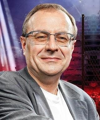Antoni Dudek w trakcie wystąpienia publicznego lub nagrania medialnego, podkreślające jego rolę jako historyka i politologa aktywnego w mediach, popularyzującego wiedzę o historii Polski.