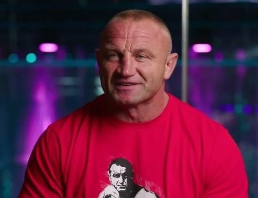 Alt: Mariusz Pudzianowski podczas walki MMA w klatce KSW, zadający cios, ukazujący jego siłę i dynamikę.