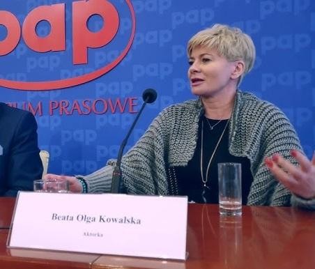 Beata Olga Kowalska na scenie teatralnej, w dynamicznej pozie aktorskiej.